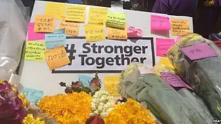 Blomster efterladt på række med sedler på forskellige sprog ved Erawan-helligdommen den 19. august (VOA).