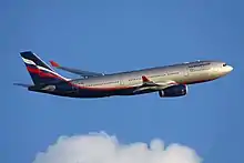 Et Aeroflot-fly i sølv, hvid, blå og rød efter takeoff flyver på en blå himmelbaggrund.