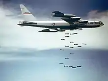 B-52F kaster bomber over Vietnam mens himlen er blå og skyerne hvide.