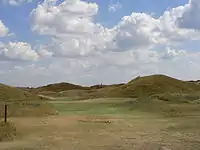 Hul 5, er 164 meter lang, blindes Par 3. Den lyse pøl til højre viser spillelinjen, til venstre for den signaliserer det sænkede jernbanesignal et frit green.