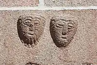 Udhuggede mandshoveder i granitkvader på Ålum kirkes sydmur