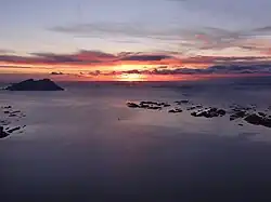 Karlsøyfjorden med øgruppen Karlsøyvær til venstre og Landegode i midten. I det fjerne lige under solen ligger øgruppen Helligvær. De sydligste holme ud for Kjerringøy ses i midten af den venstre billedkant.