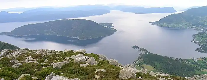Kvinnheradsfjorden fra Snilstveitøy (i venstre halvdel af bildet) og innover til Varaldsøy som splitter fjordløbet i Øynefjorden (vestlige fjordarm) og Sildafjorden. Nede til højre skimtes byen Dimmelsvik, og  i højre billedkant Seimsfoss  og Rosendal. Set fra Solfjellet mellem Uskedalen og Omvikdalen.