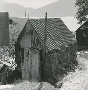 Sider af tilhugne sten. Gavlene oprindelig træ, nu bølgeblik.)