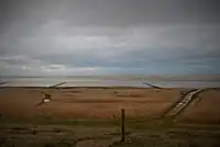 Vest for Mandø By. I forgrunden Stormflodssøjlen. I baggrunden anes Koresand.