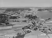 Luftfoto, formentlig fra 1950'erne, af den nordlige del af Nøtterøy med Teie foran og Tønsberg i baggrunden med fjordbassinet Træla til højre.Foto: Widerøe/Vestfoldmuseene