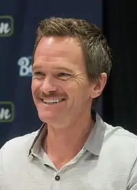 A man with dark blonde hair and mustache smiles away from the camera