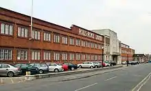 Image of a red brick building with a central front door, the words Rolls-Royce Limited appear above the door in white letters