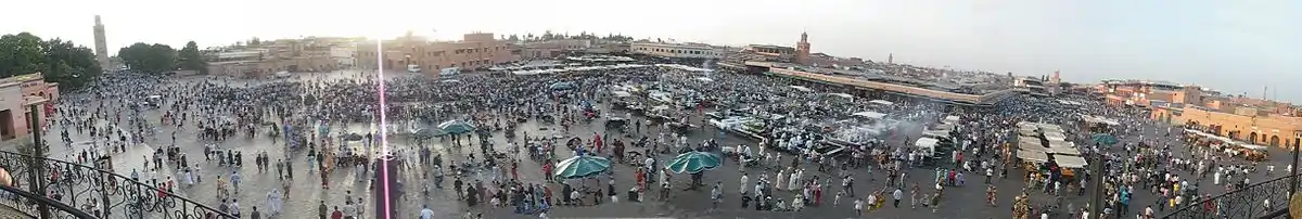 Panorama af Djemaa el Fnapladsen ved solnedgang. Koutoubia-moskéen helt til venstre. Handelskvartererne (souk) ligger bag  pladsen