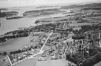 Luftfoto af Nøtterøy set fra nordøst, formentlig taget i 1950'erne, viser Teie foran, Føynland i baggrunden og del af fjordbassinet Træla til venstre.Foto: Widerøe/Vestfoldmuseene