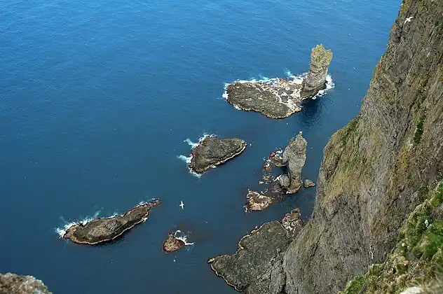 Han (dvs. Risin) står længere ude foran brændingen, og hans kone Kellingin står med spredte ben tættere på land.