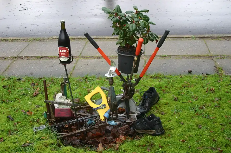 Collage af sammensvejsede haveredskaber med levende plante og trøstpræmie.