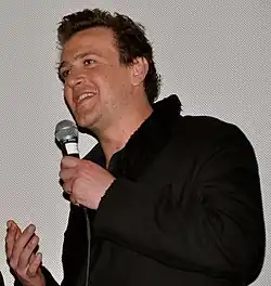 A man holds a microphone as he speaks