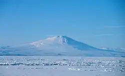 Distant view over an ice-covered sea of a conical mountain