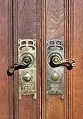 Dørhåndtag i hoveddøren med Aarhus Toldkammers initialer: AT oven i hinanden
